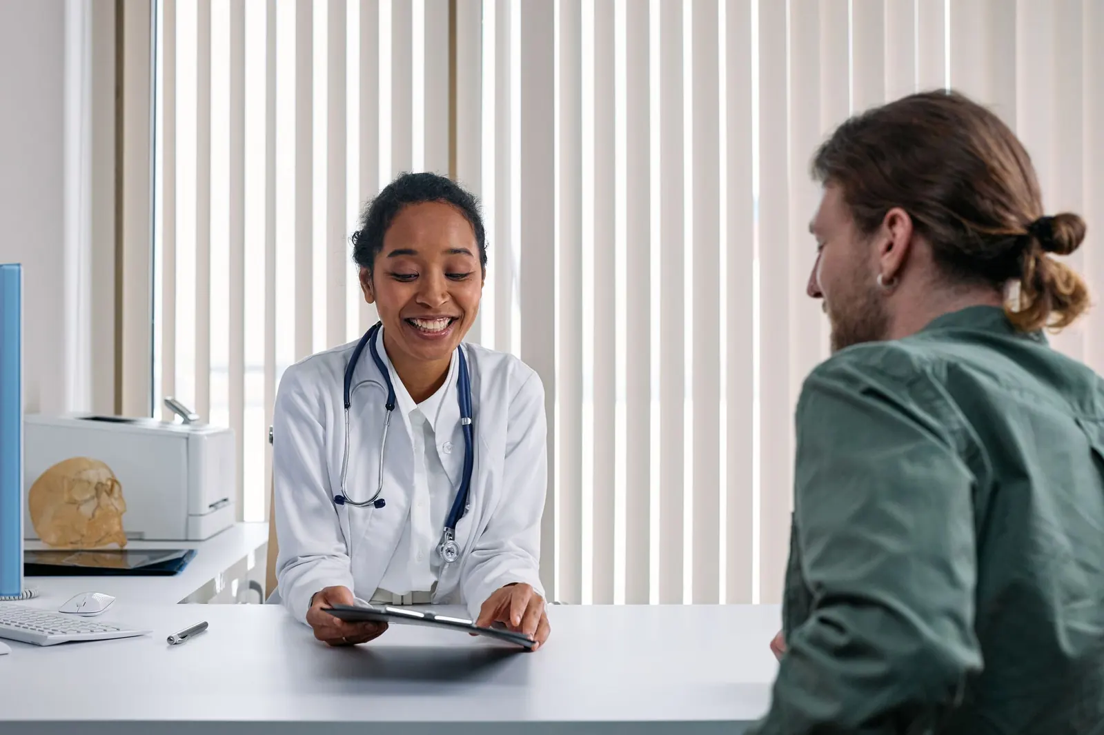 Smiling doctor talking with a patient across her desk during a consultation